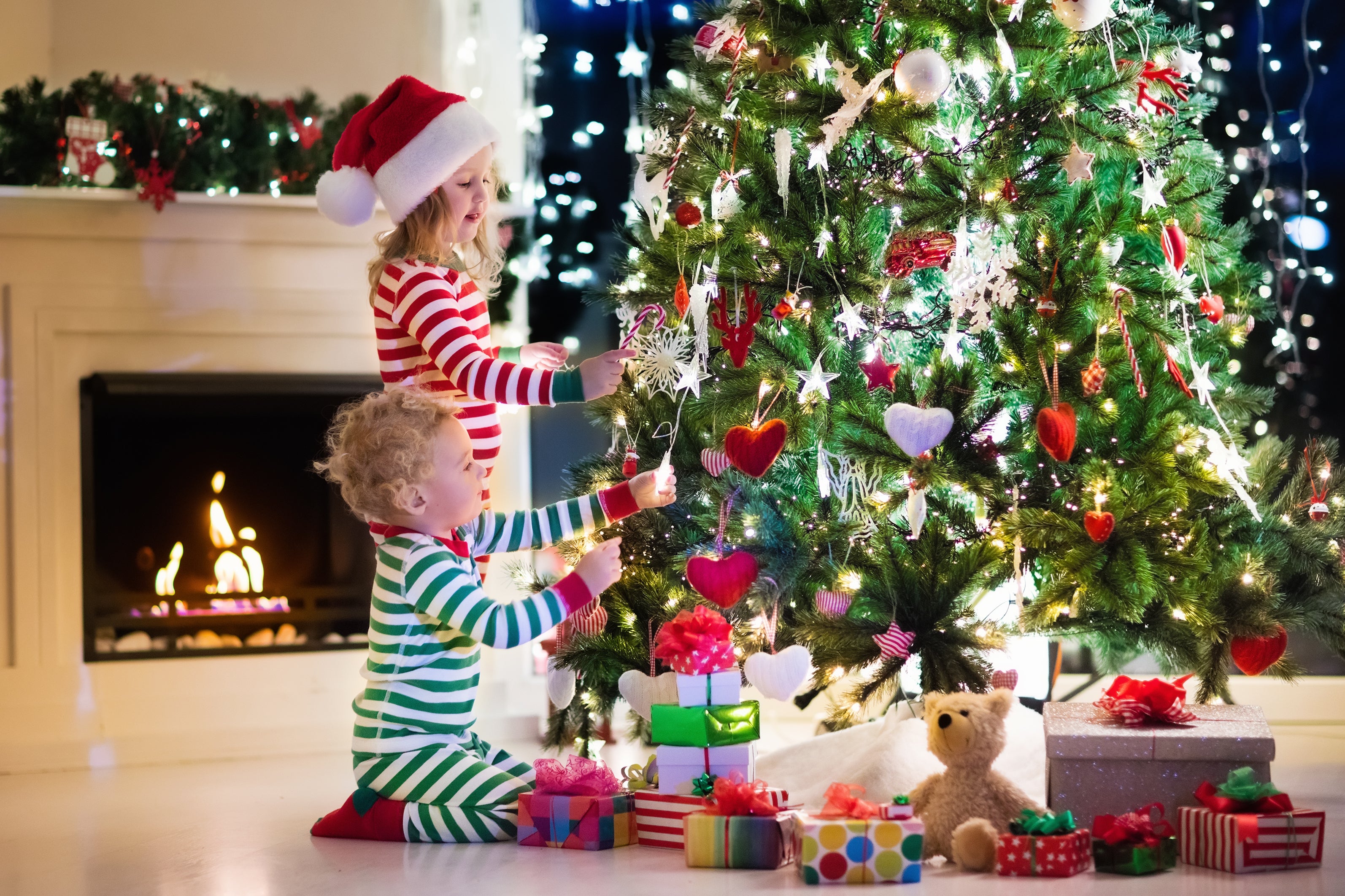 two kids placing ornaments on chirstmas tree